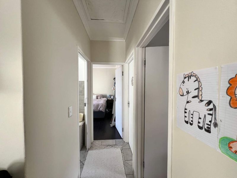 A functional hallway connecting multiple rooms, featuring tiled flooring and a ceiling access hatch.