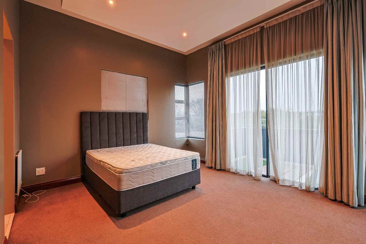 Spacious bedroom featuring neutral wall tones, plush carpeting, recessed ceiling lighting, and large sliding glass doors leading to an outdoor balcony.
