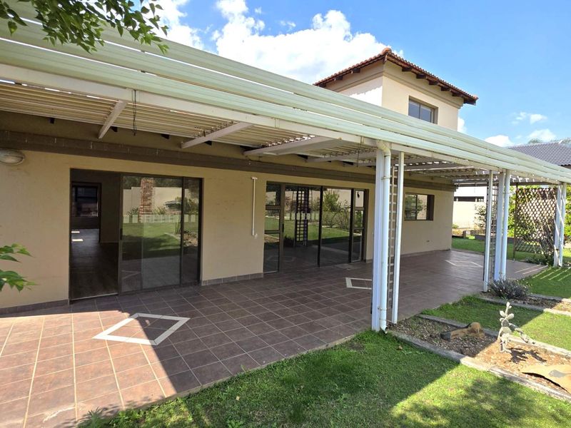 Spacious covered patio featuring tiled flooring and direct access to the garden through large sliding glass doors, ideal for outdoor entertaining.