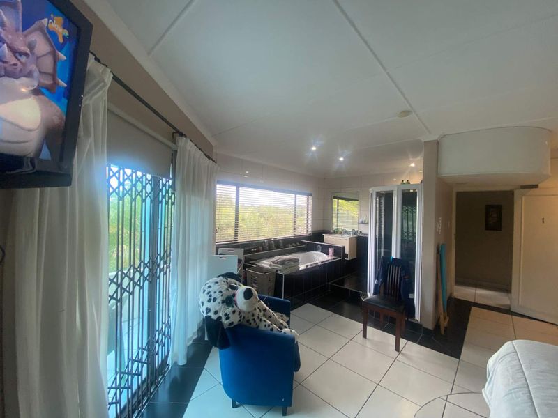 Spacious bathroom featuring a built-in bathtub, separate shower enclosure, vanity, and tiled flooring with access to an outdoor area via a security gate.