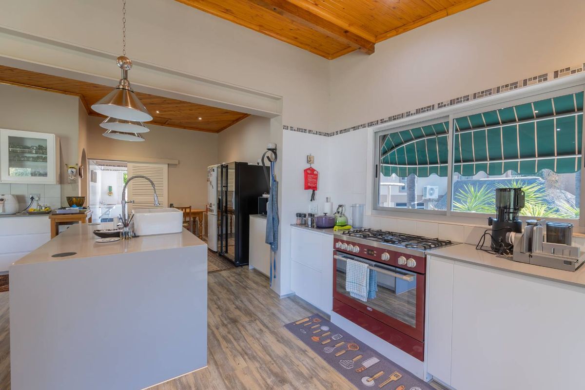 Modern kitchen featuring a central island with a farmhouse sink, gas stove, and timber-clad ceilings, offering a bright and functional cooking space.
