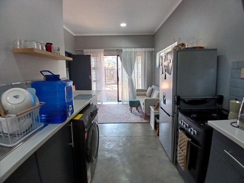 Open-plan kitchen and living area featuring modern cabinetry, built-in stove, laundry connections, and direct access to an outdoor patio through sliding glass doors.