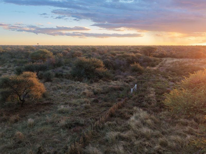 An aerial view of the expansive natural landscape and vegetation on the small holding property at sunset.