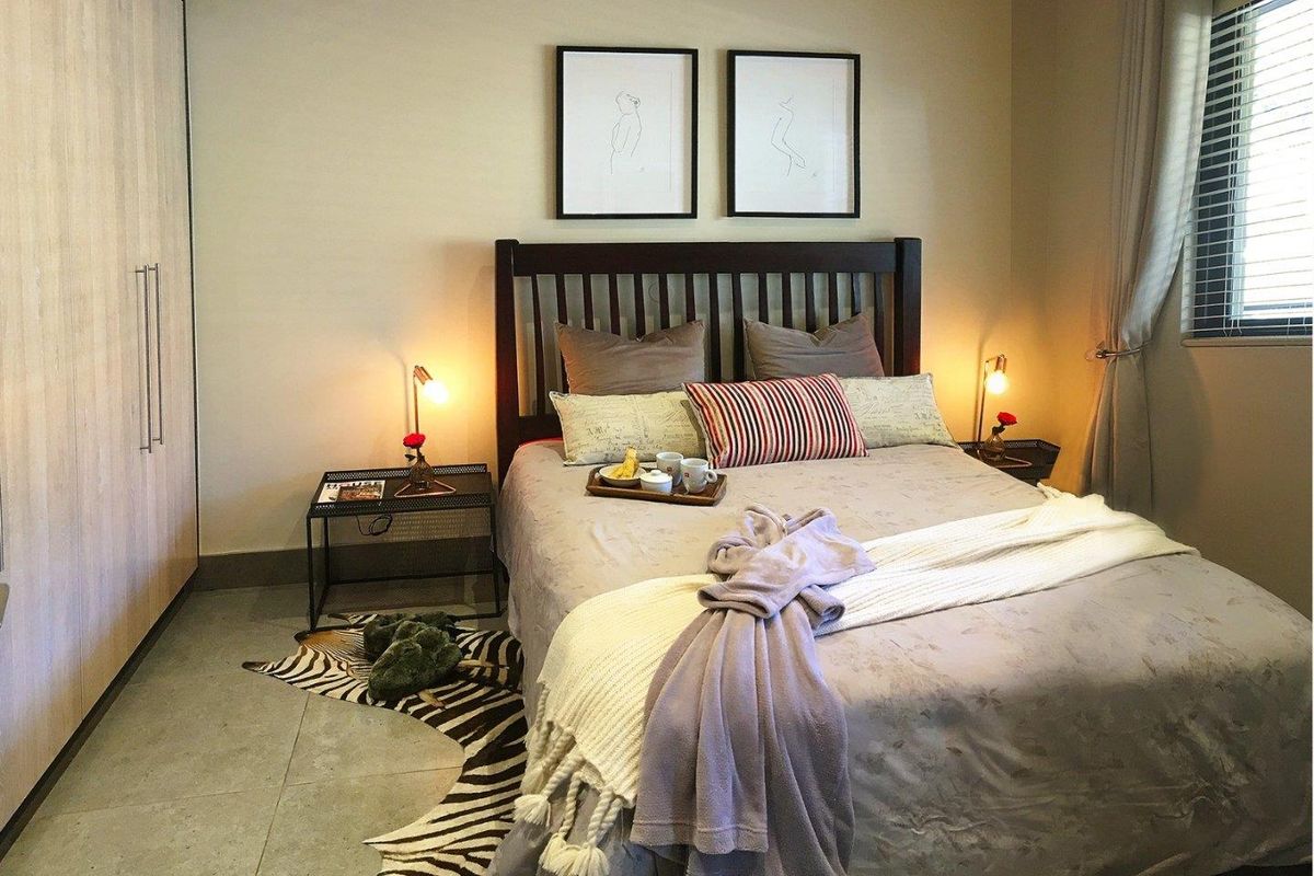 A well-maintained bedroom featuring neutral tiled flooring, a large built-in wardrobe, and venetian blinds for privacy.