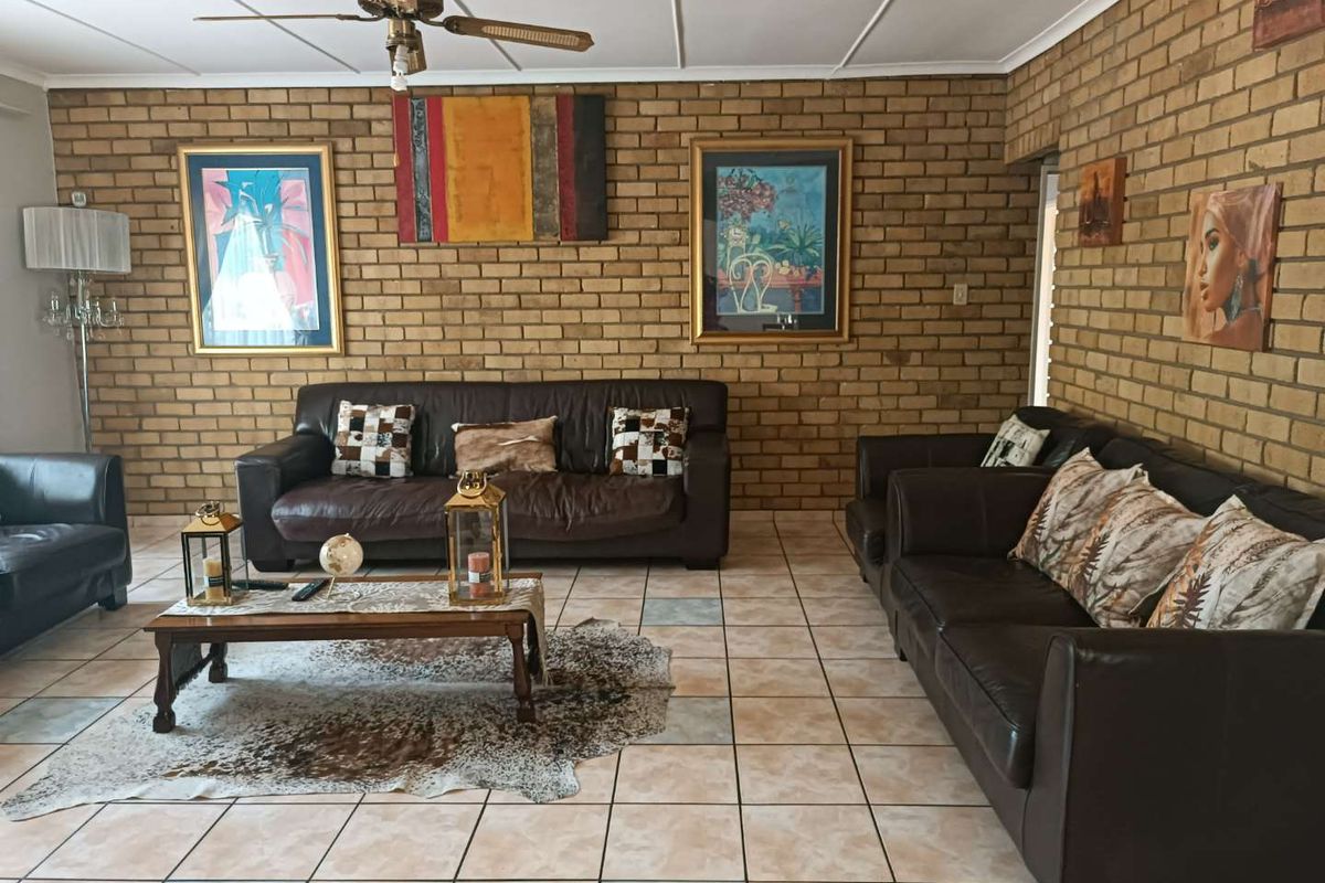 Spacious living room featuring exposed brick walls, ceramic tile flooring, and a ceiling fan.