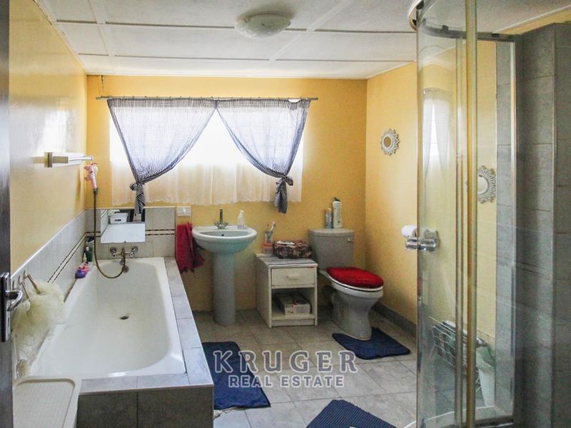 A functional bathroom featuring a built-in bathtub, separate shower enclosure, pedestal basin, and toilet with tiled flooring and wall finishes.