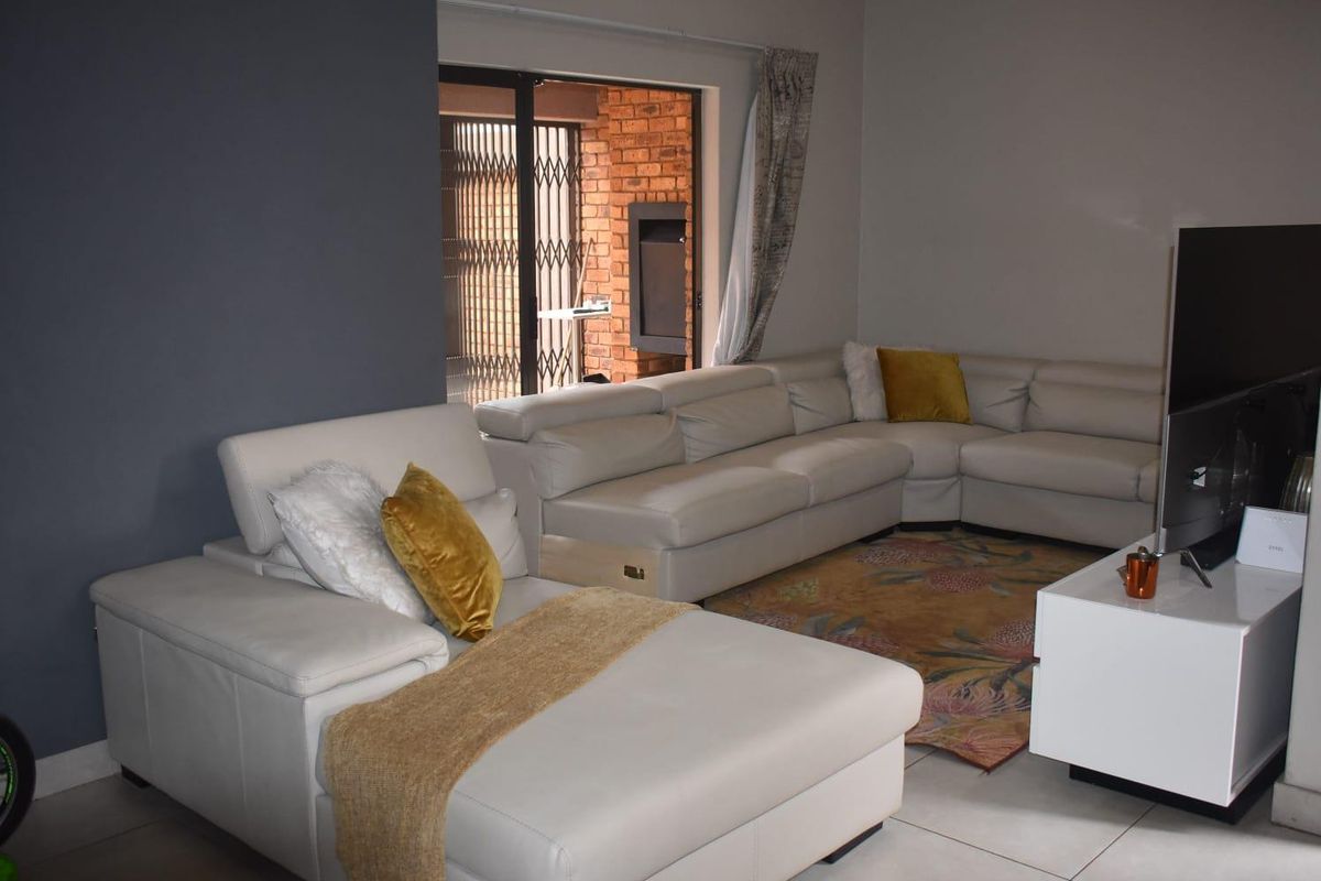 Spacious living room featuring tiled flooring, a feature wall, and sliding glass doors providing access to an outdoor patio area.