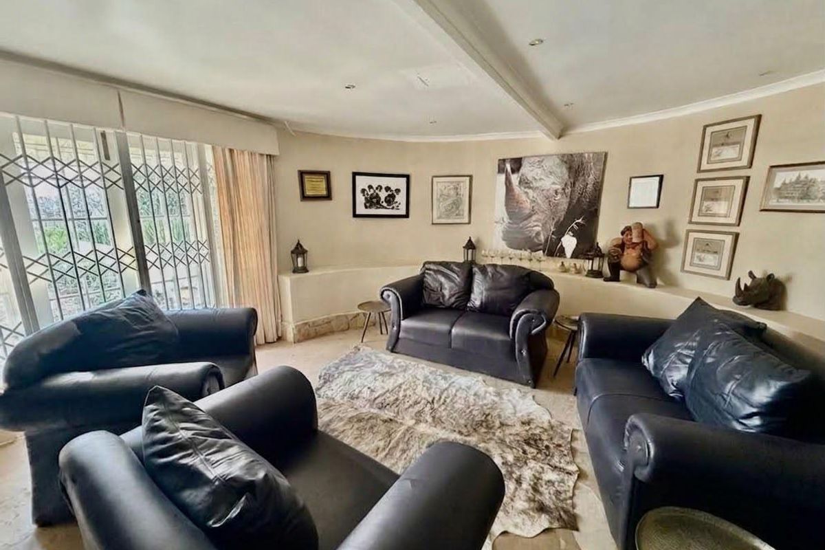A comfortable living room featuring a built-in ledge, tiled flooring, and large sliding doors with security gates providing access to the exterior.