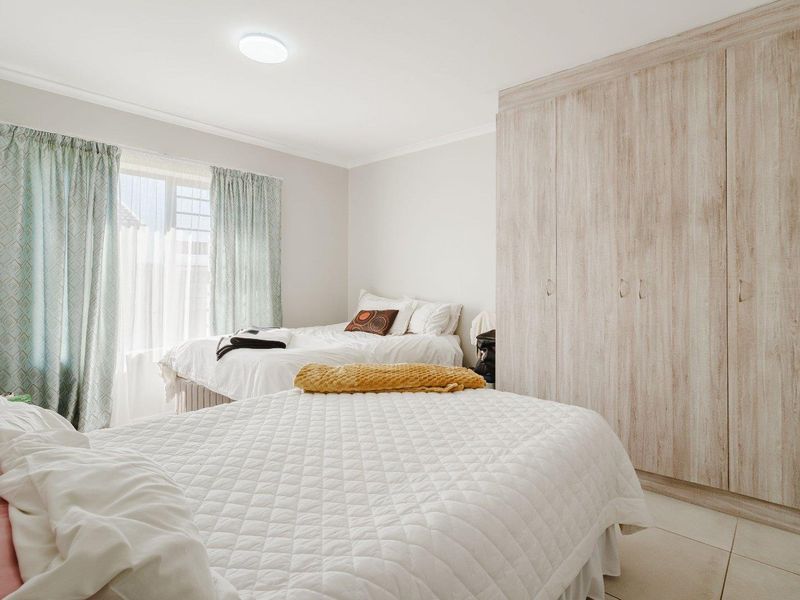A well-lit bedroom featuring neutral walls, tiled flooring, and ample built-in cupboard storage space.