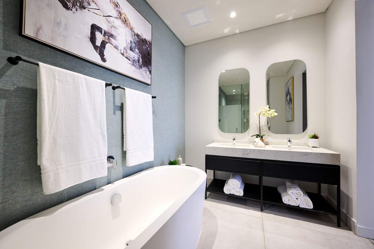 Modern bathroom featuring a freestanding bathtub, double vanity with stone countertop, dual mirrors, and contemporary fixtures.