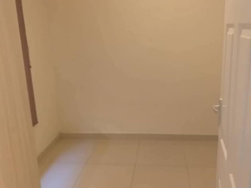 An empty bedroom featuring neutral tiled flooring and a standard internal door, providing a blank canvas for interior design.