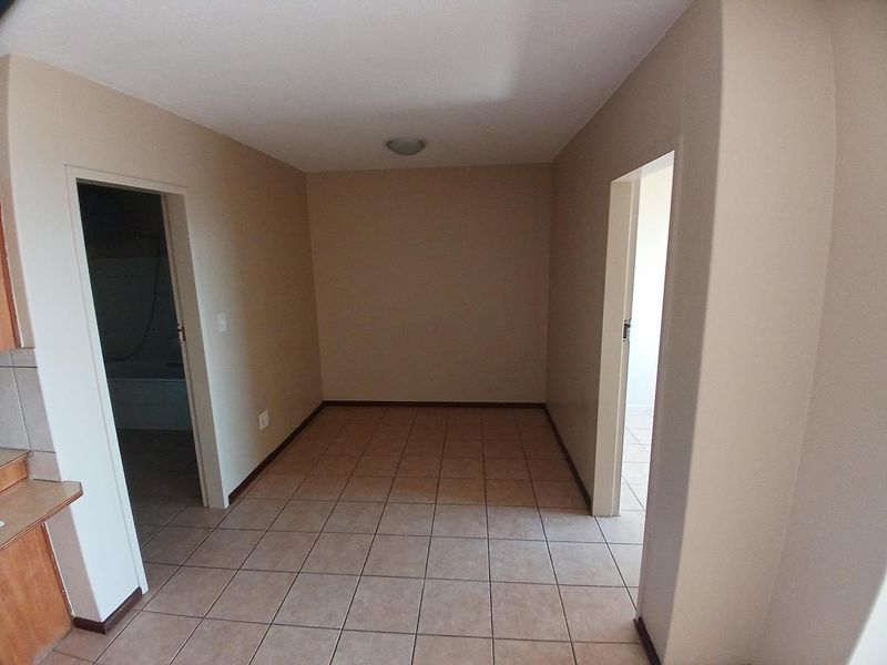 An empty, tiled hallway area providing access to adjacent rooms, featuring neutral wall tones and a simple ceiling light fixture.