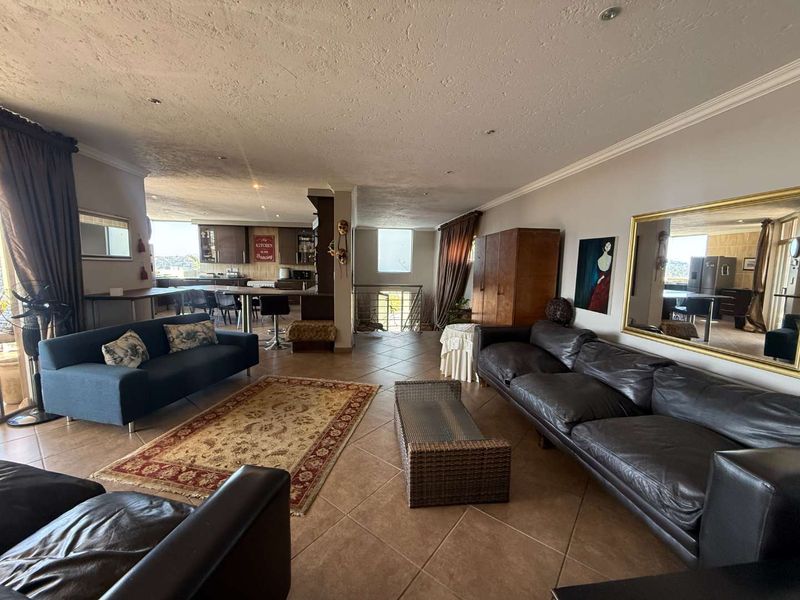 Spacious open-plan living area featuring tiled flooring, recessed lighting, and crown molding, seamlessly connecting to the kitchen space.