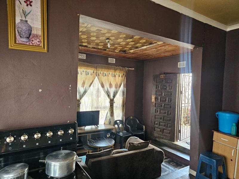 Open plan living area featuring a built-in stove, wooden ceiling detail, and direct access to the exterior through a secure timber door.