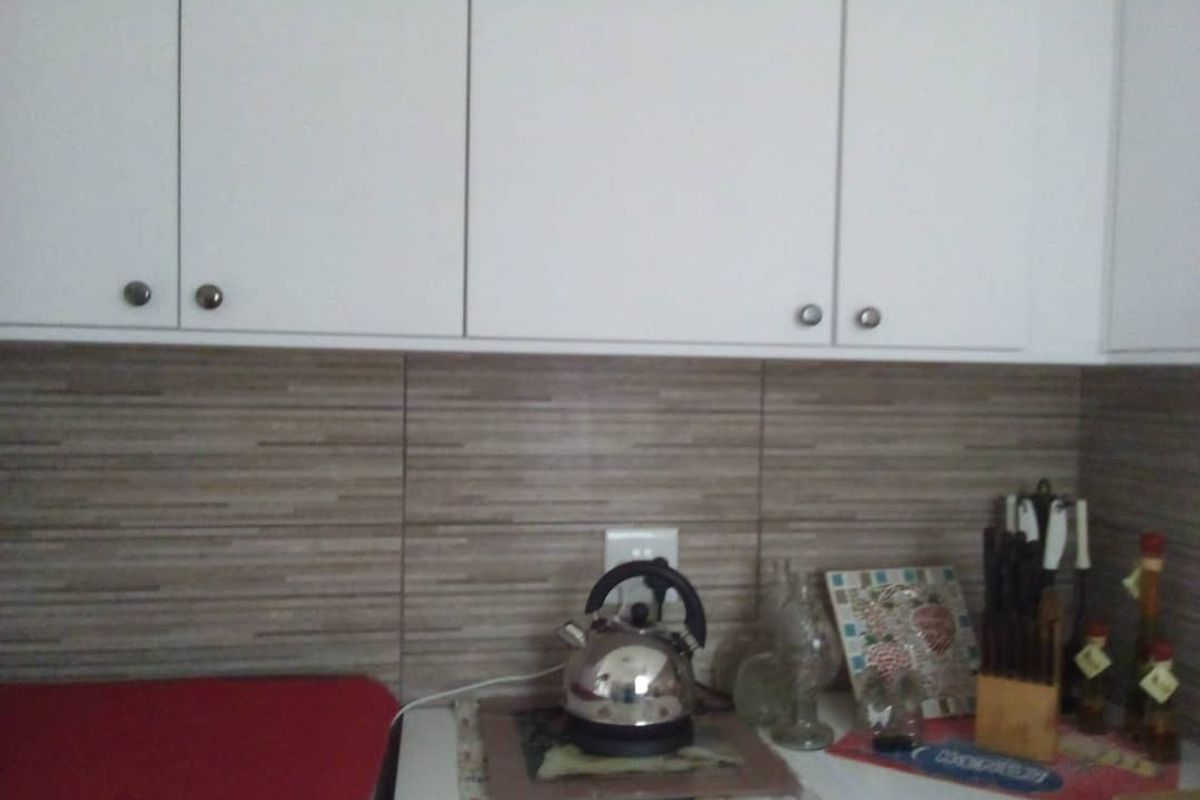 A kitchen area featuring white upper cabinetry and a horizontal tiled backsplash.