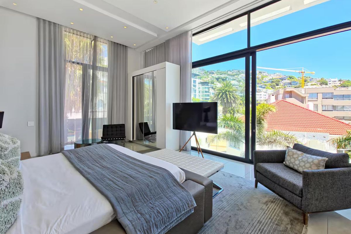 Spacious modern bedroom featuring floor-to-ceiling windows, built-in wardrobe, and expansive views of the surrounding neighborhood.
