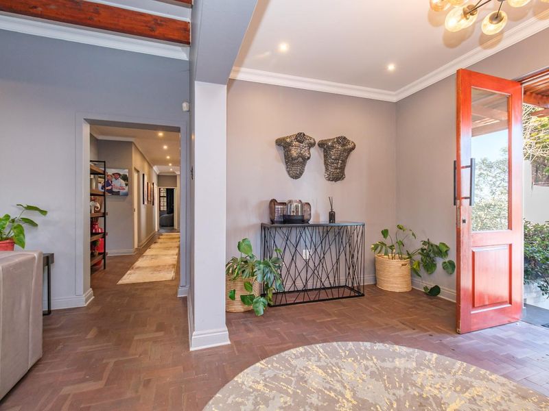 Welcoming entrance hall featuring elegant herringbone parquet flooring, crown molding, and a solid timber front door leading to a connecting hallway.