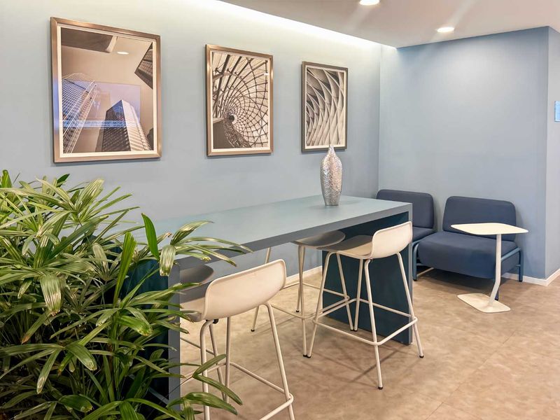 A modern office breakout area featuring recessed ceiling lighting and tiled flooring, designed for collaborative work or casual meetings.