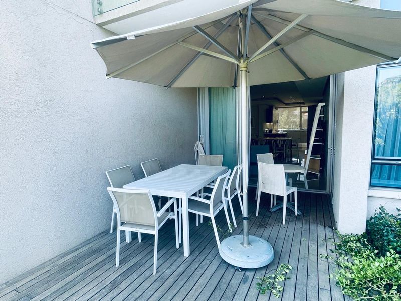 A covered outdoor patio featuring timber decking and sliding glass doors, providing a seamless transition to the interior living space.