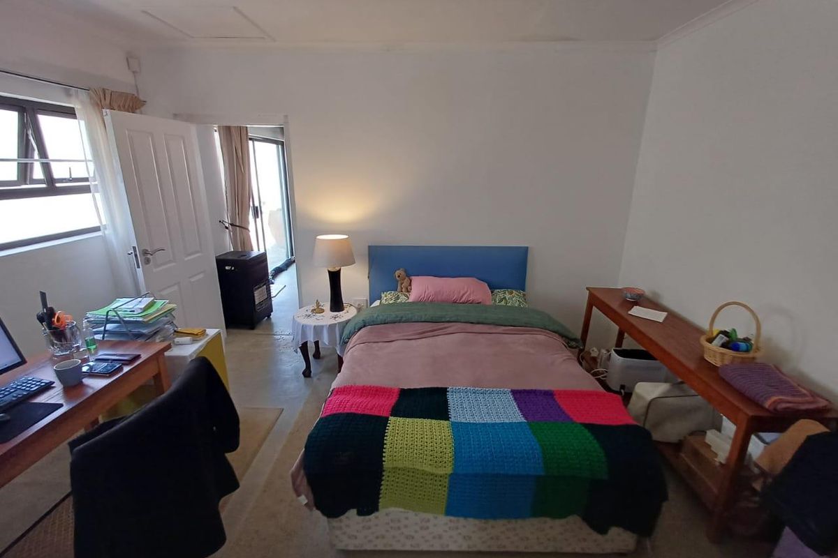 A functional bedroom featuring a casement window, coved ceiling, and direct access to an adjacent space.
