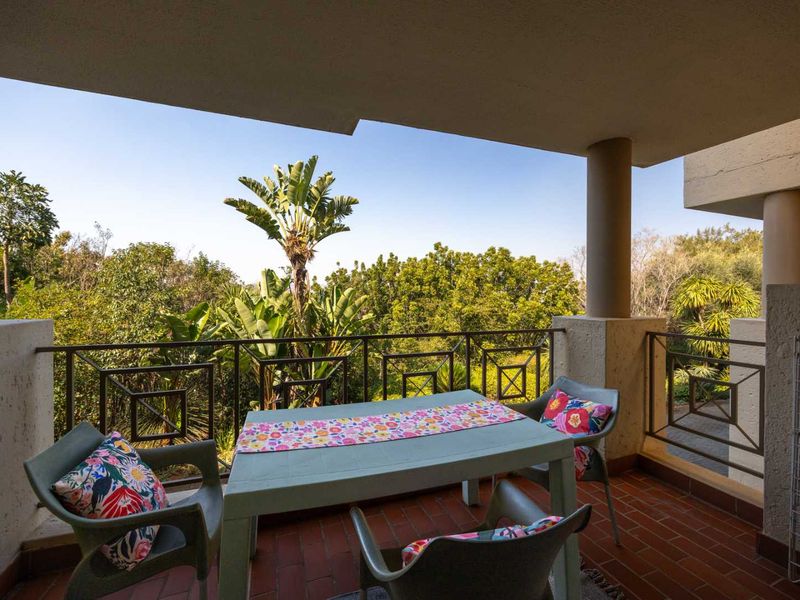 A covered balcony featuring terracotta tiling and metal balustrades, offering a pleasant outdoor space with views of the surrounding greenery.