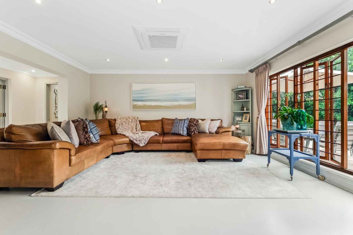 Spacious living room featuring recessed ceiling lighting, a central air conditioning unit, and large wooden-framed glass doors providing access to the outdoor area.