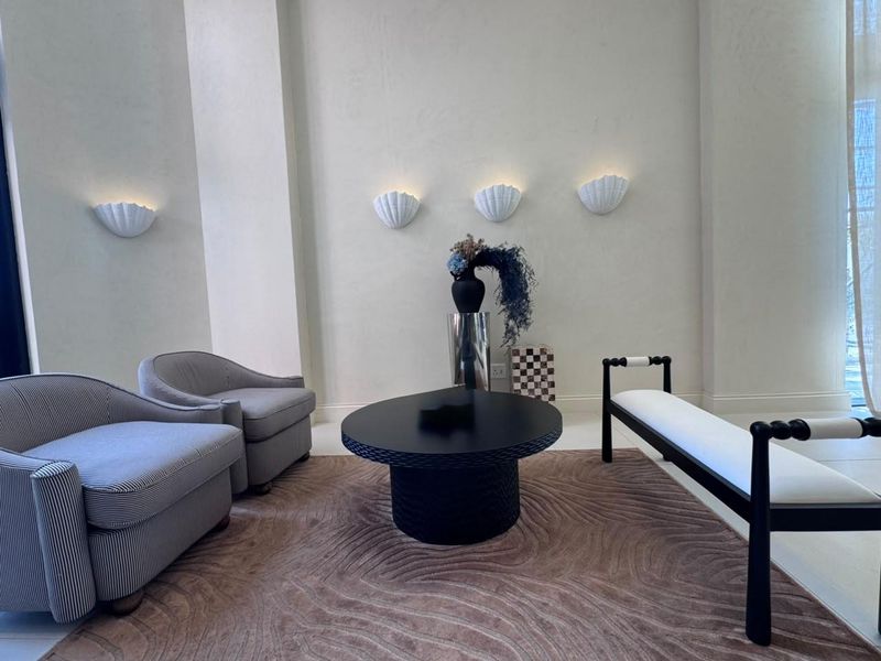 A well-lit living area featuring decorative wall sconces and neutral wall finishes, creating a sophisticated and inviting atmosphere.