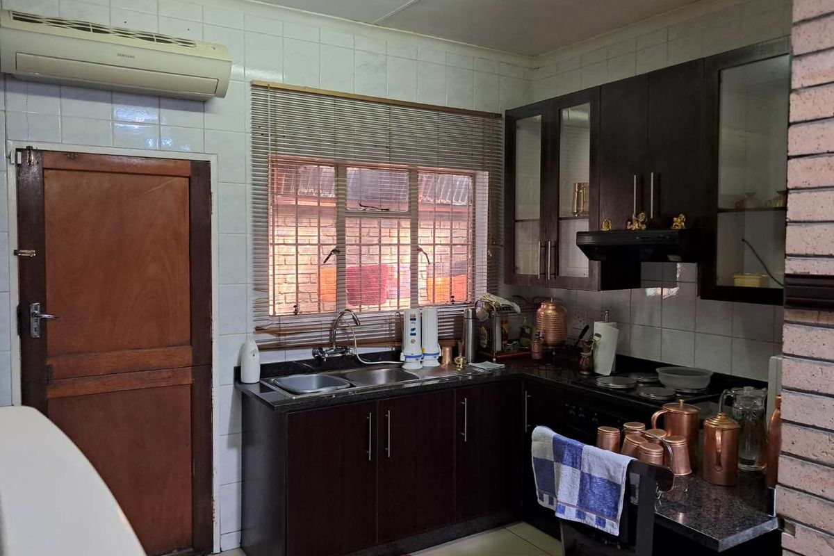 A functional kitchen featuring dark cabinetry, granite countertops, a double sink, and a built-in extractor fan.