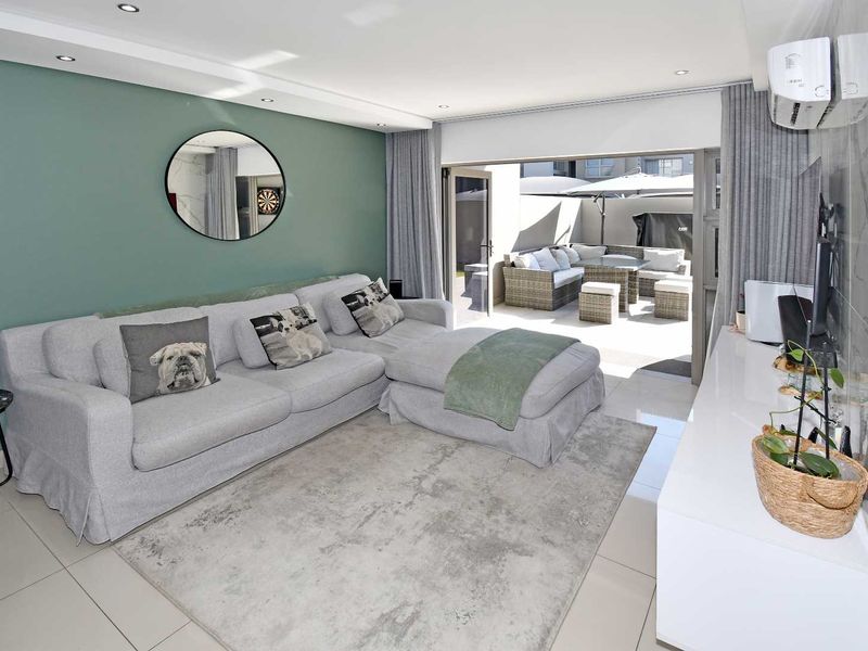 Modern living room featuring tiled floors, recessed lighting, and a split-system air conditioner, with seamless access to an outdoor patio area.