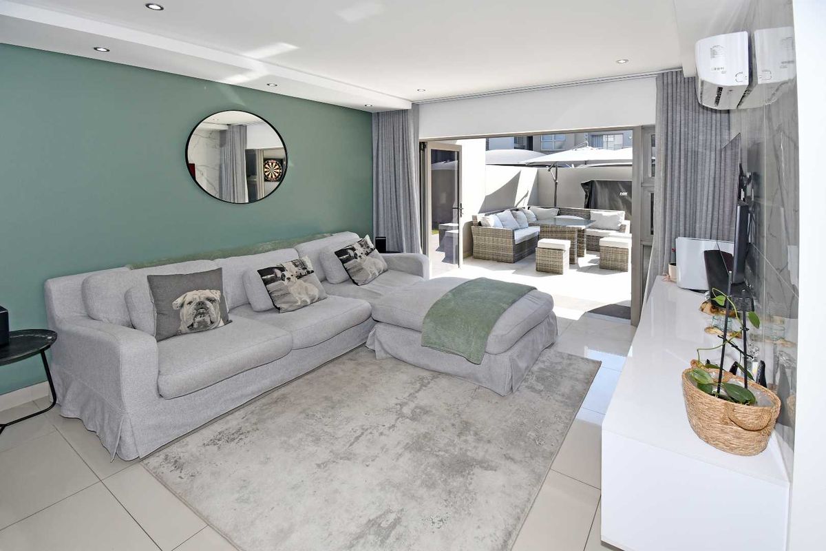 Modern living room featuring tiled floors, recessed lighting, and a split-system air conditioner, with seamless access to an outdoor patio area.