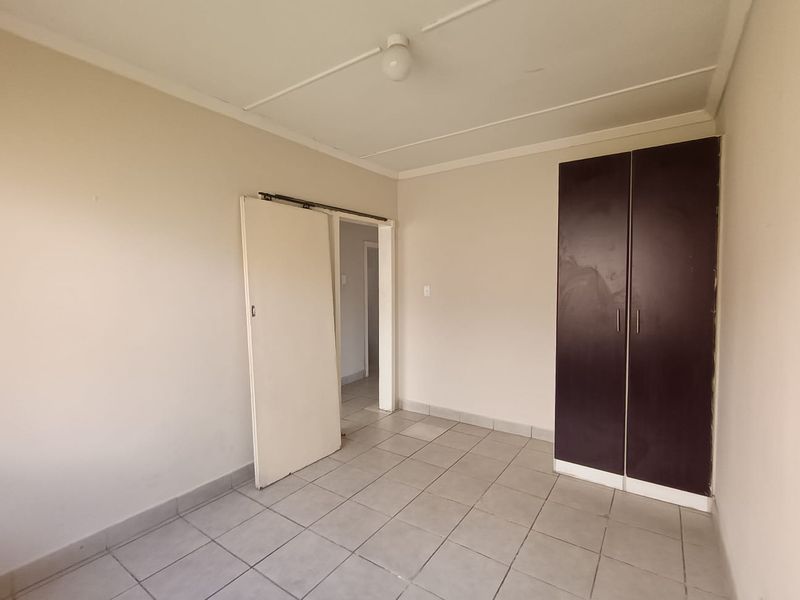 An empty bedroom featuring tiled flooring and a built-in wardrobe, providing a blank canvas for personalization.