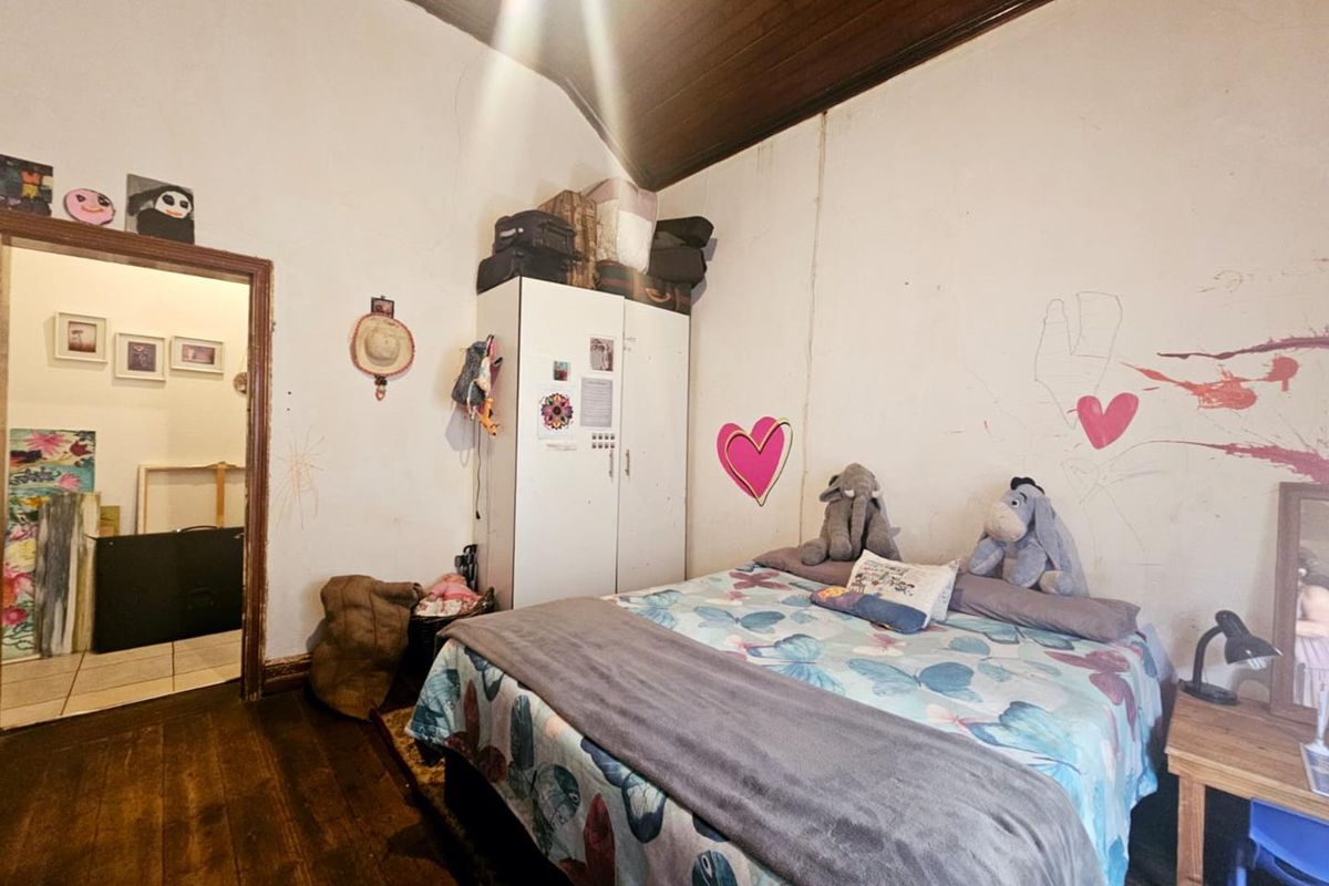 A bedroom featuring dark timber flooring and a vaulted timber ceiling, requiring cosmetic updates to the wall finishes.