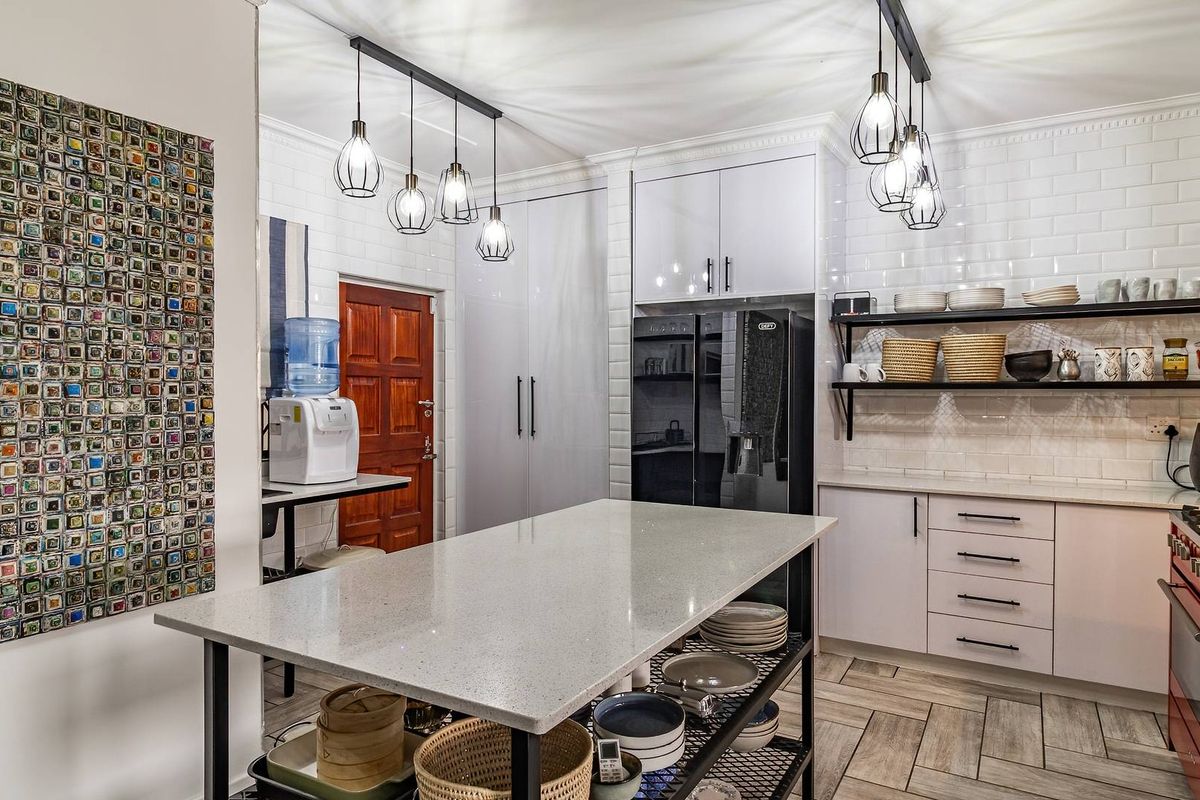 Modern kitchen featuring a central island with quartz countertop, subway tile backsplash, open shelving, and contemporary pendant lighting.
