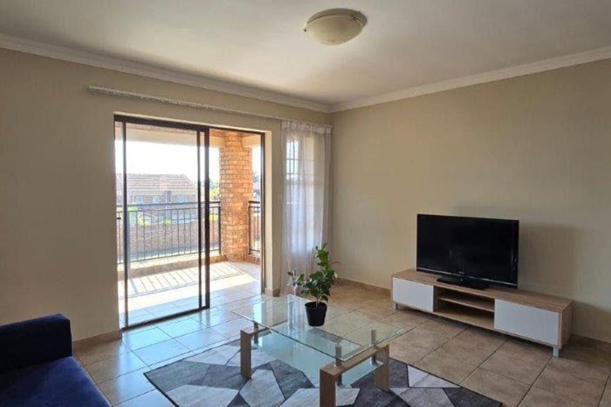 A living room featuring tiled flooring, neutral walls, and a sliding glass door providing access to an outdoor balcony area.
