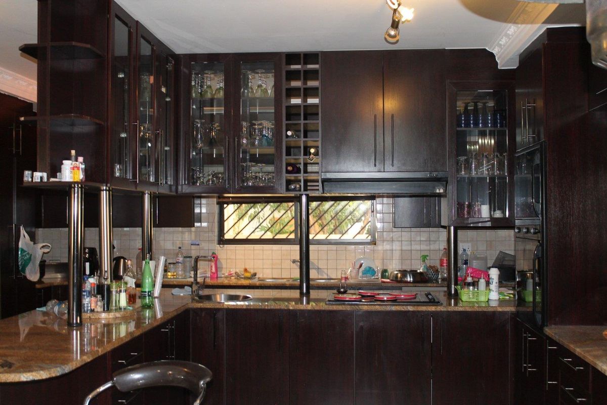 A kitchen featuring dark wood cabinetry, granite countertops, a built-in hob, and glass-fronted display cabinets.