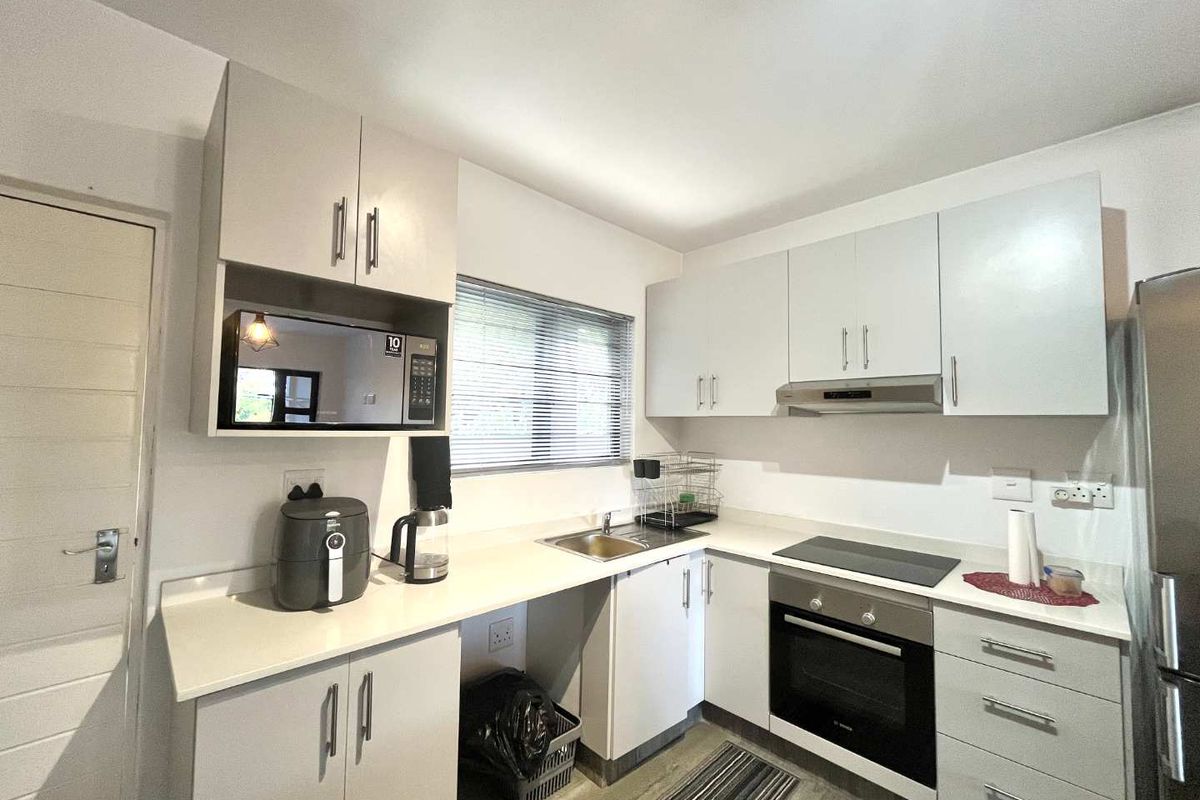Modern kitchen featuring white cabinetry, stone-look countertops, built-in oven, electric hob, and stainless steel extractor fan.