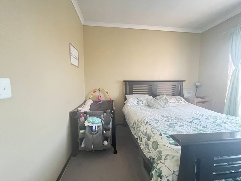A standard bedroom featuring neutral wall finishes, coving, and a window with curtain rails.