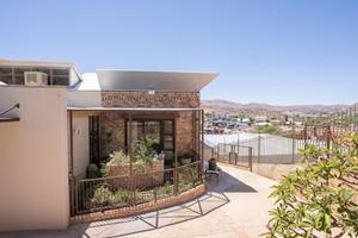Rear exterior view of the property featuring stone cladding, a paved patio area, and metal railings with scenic landscape views.