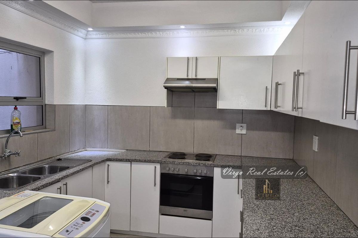 Modern kitchen featuring white cabinetry, granite countertops, built-in oven with hob, extractor fan, and a double bowl stainless steel sink with tiled splashback.
