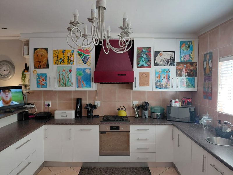 A functional kitchen featuring white cabinetry, dark laminate countertops, a gas hob with an extractor fan, and tiled backsplash.