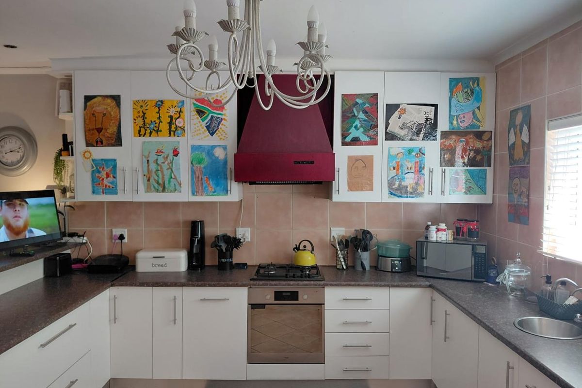 A functional kitchen featuring white cabinetry, dark laminate countertops, a gas hob with an extractor fan, and tiled backsplash.