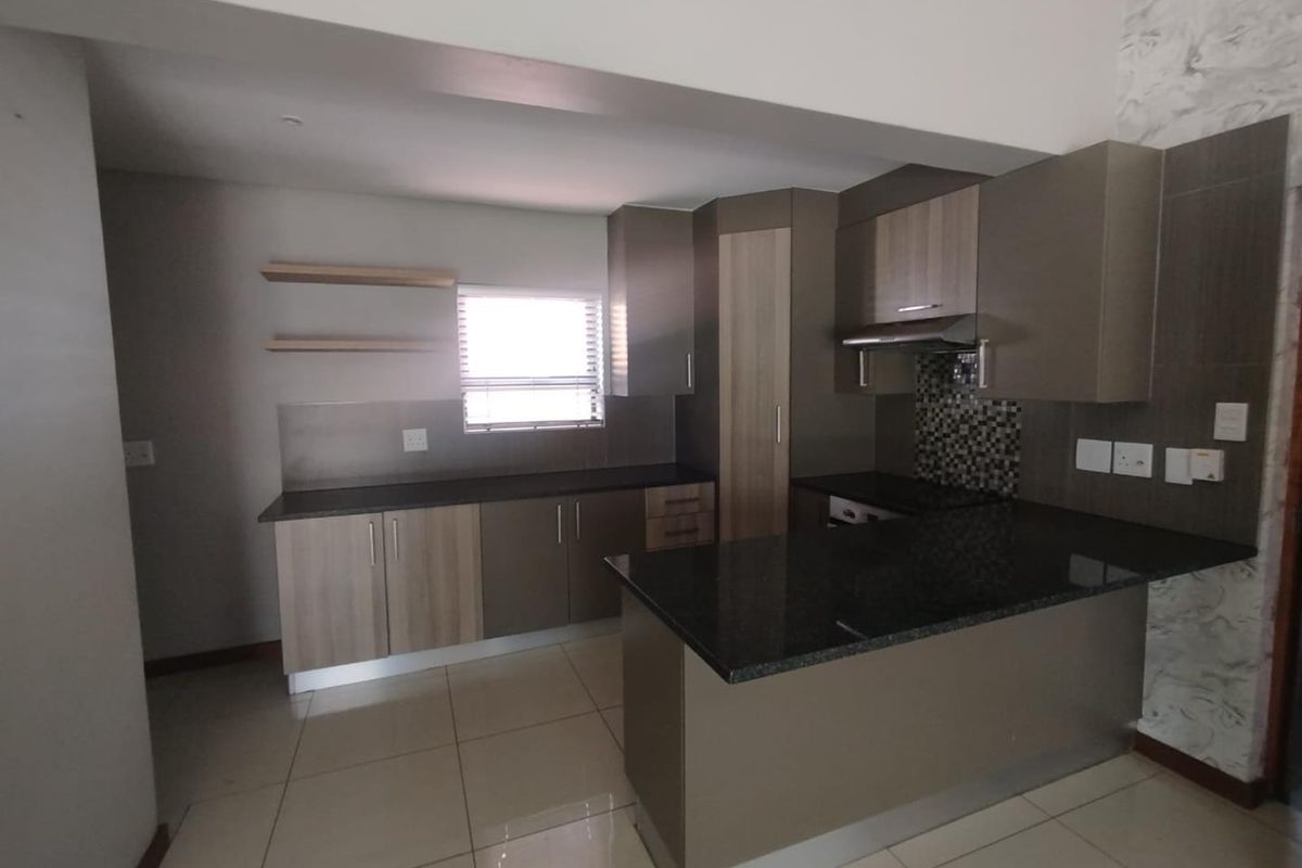 Modern kitchen featuring granite countertops, built-in cabinetry, a mosaic tile backsplash, and an integrated extractor fan with tiled flooring throughout.