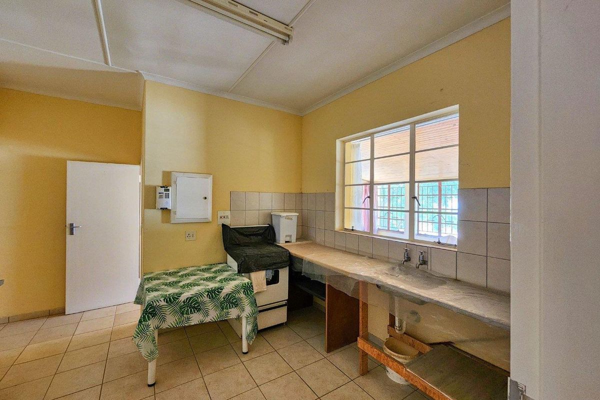 A functional kitchen or utility space featuring tiled flooring, a built-in sink, and basic cabinetry, offering potential for modernization and renovation.