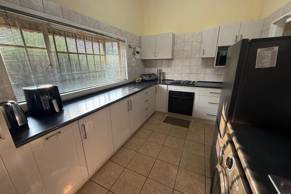 Functional kitchen featuring white cabinetry, dark laminate countertops, built-in oven, gas hob, and tiled flooring with ample natural light.