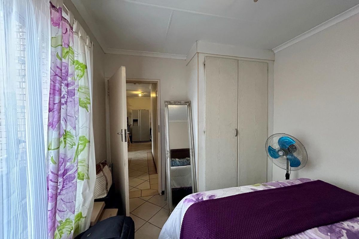 A functional bedroom featuring tiled flooring, a built-in wardrobe, and direct access to the hallway.