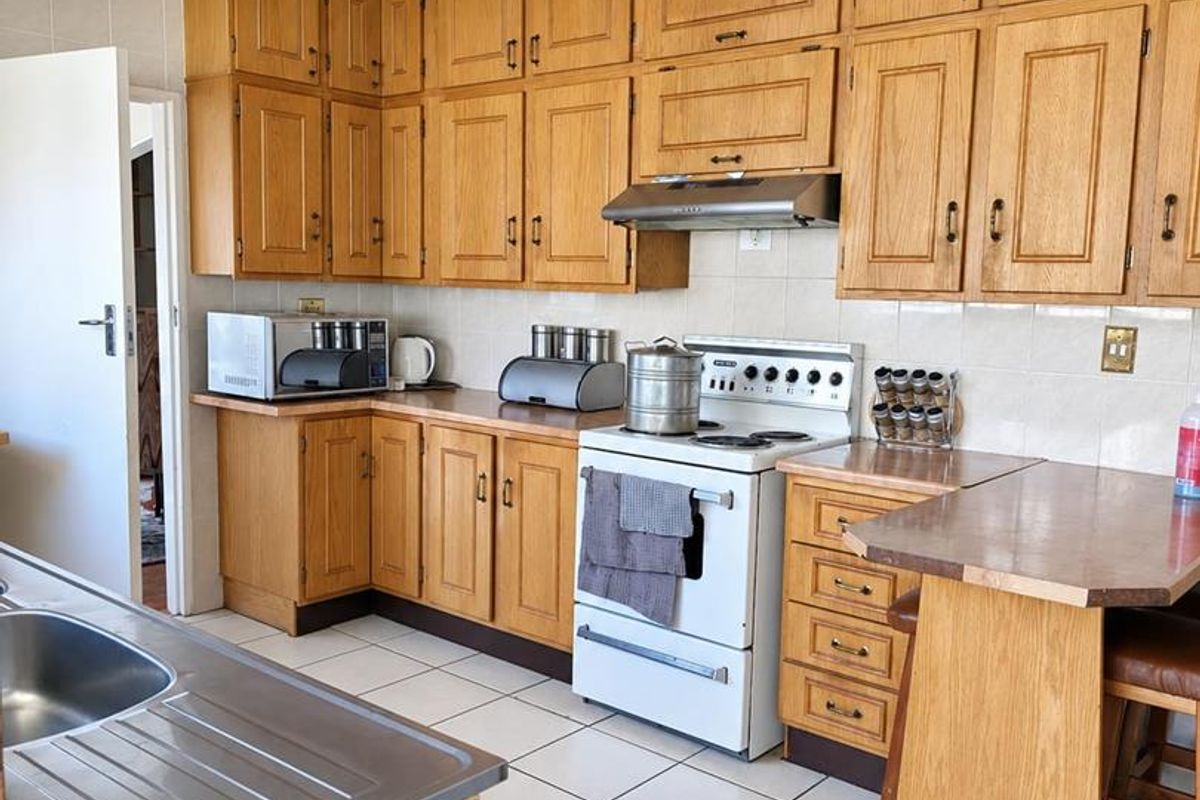 A functional kitchen featuring traditional wooden cabinetry, tiled flooring, a breakfast counter, and a built-in extractor fan over the stove area.