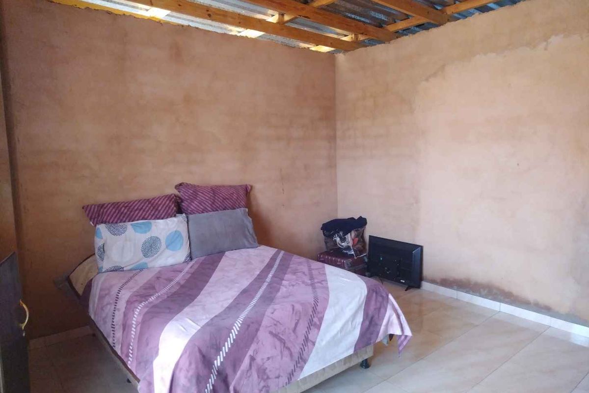 A bedroom featuring tiled flooring and exposed timber roof rafters, currently requiring ceiling installation and wall finishing to improve the overall condition.