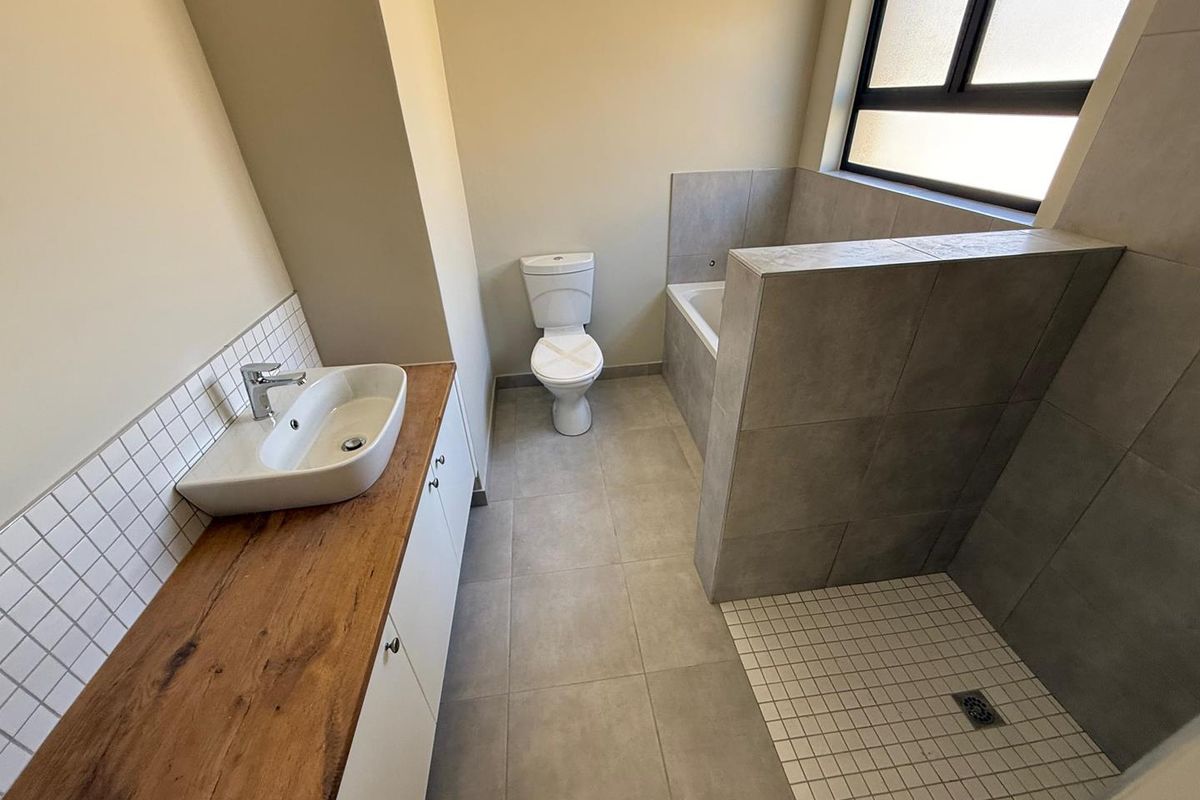 Modern bathroom featuring a vessel sink on a wooden vanity, a walk-in shower with tiled surround, and a separate bathtub.