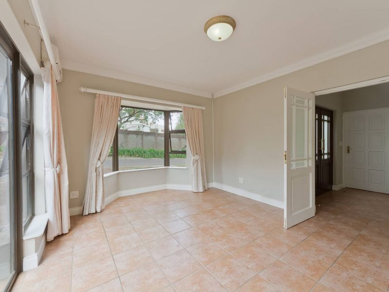 A bright, empty living room featuring tiled flooring, a large bay window, and direct access to an outdoor area via a sliding glass door.