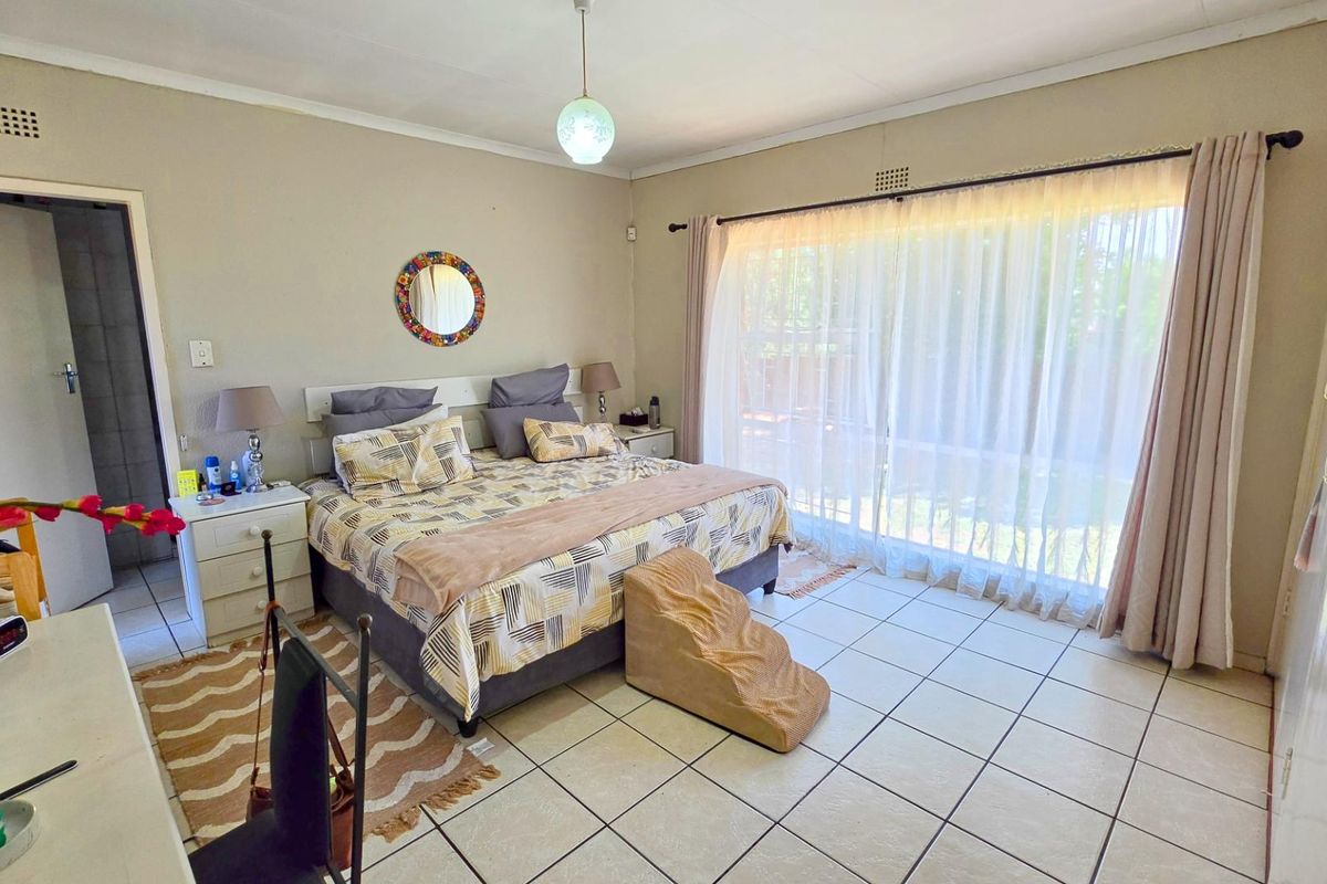 Spacious bedroom featuring tiled flooring, a built-in headboard, and large sliding glass doors that provide ample natural light and access to the outdoors.